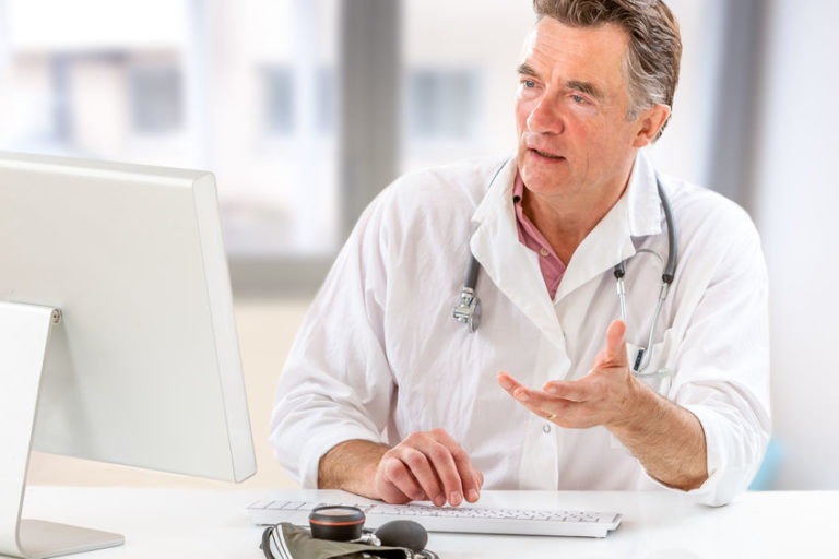 Online medical consultation: Doctor expplaining diagnosis while sitting in hfront computer with patient